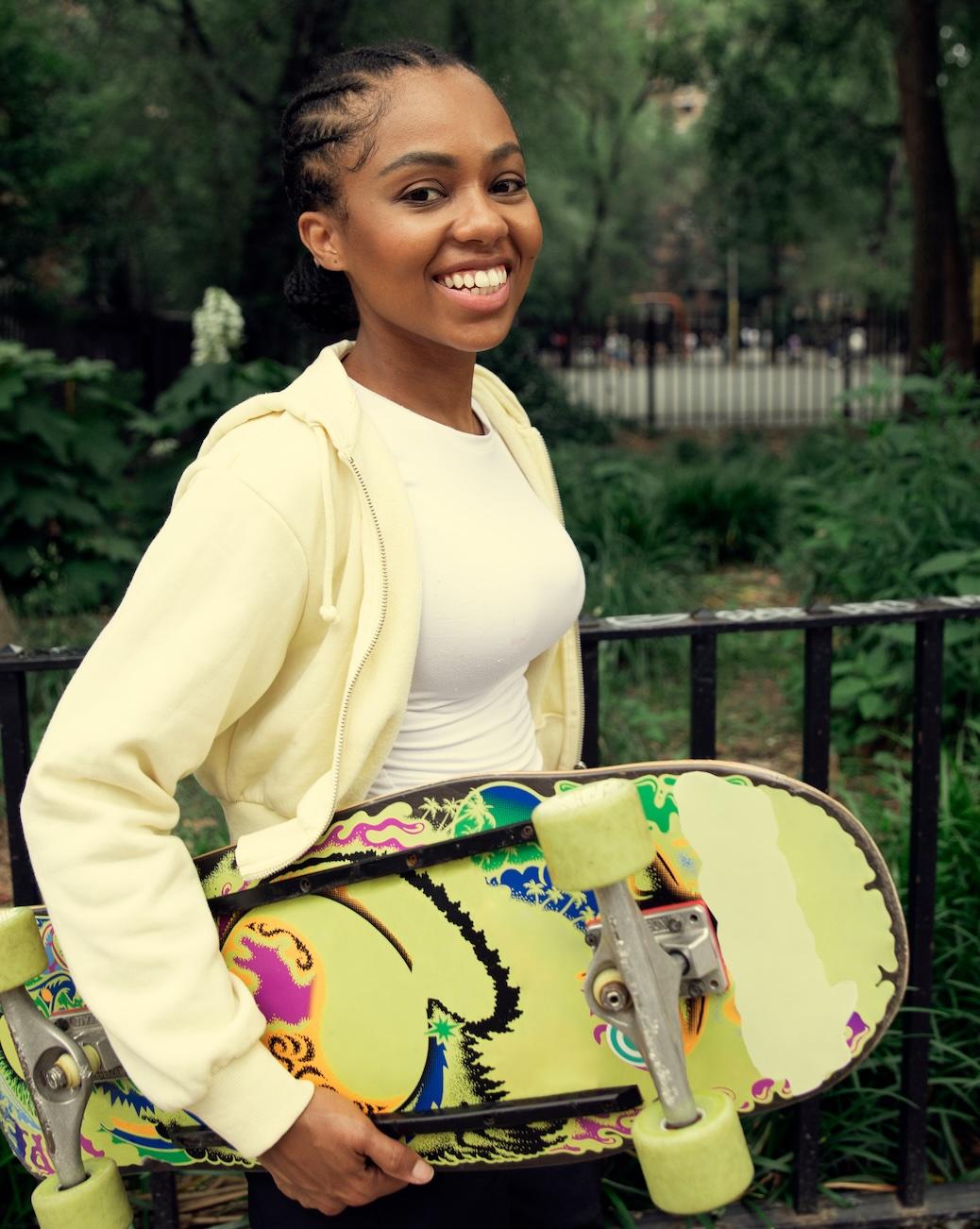 Smiling woman carrying a skateboard in a park