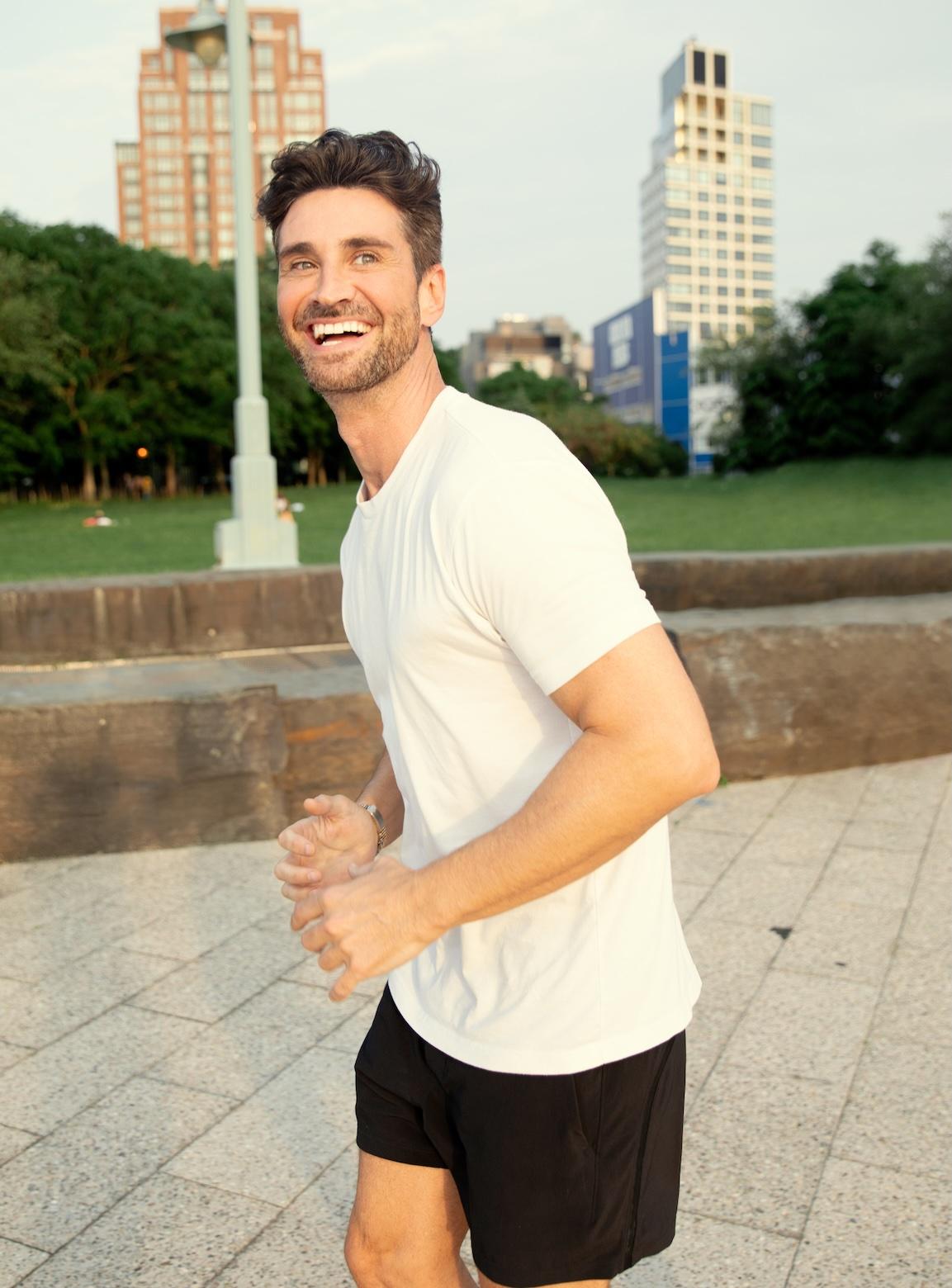 Man jogging and smiling in a city park