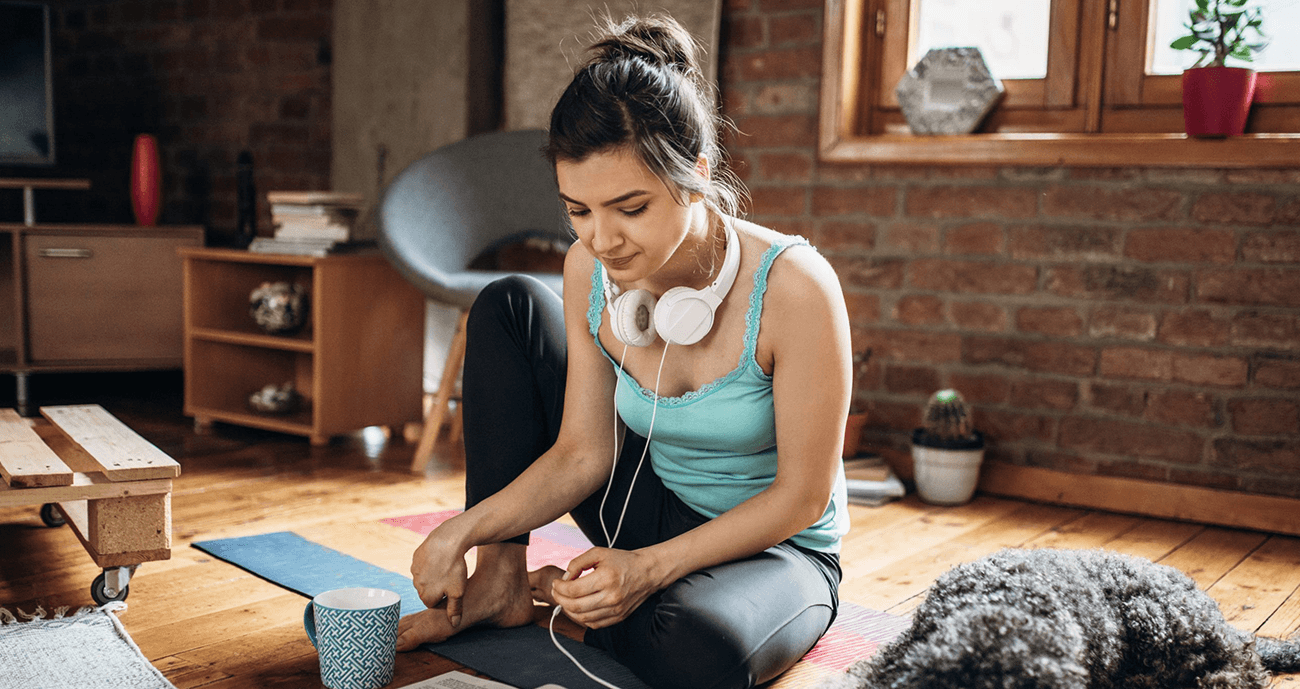 Woman wearing activewear, sitting down with her dog.