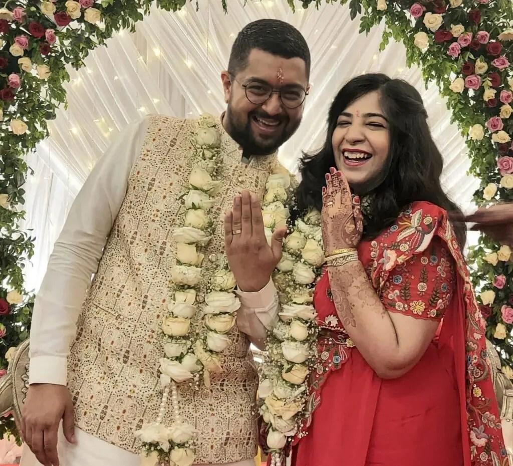 Viraj and Aakriti standing holding their hands up to show their rings.